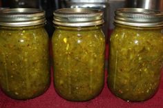 three jars filled with pickles sitting on top of a table