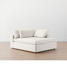 a white couch sitting on top of a hard wood floor next to a white wall