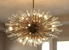 a large chandelier hanging from the ceiling in a room with windows and sunlight coming through