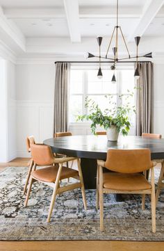 a dining room table with chairs and a rug on the floor in front of it