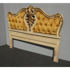 an antique style bed frame with gold upholstered fabric