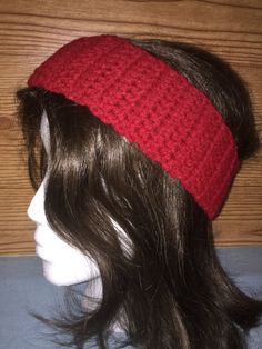 a mannequin head wearing a red knitted hat on top of a wooden table