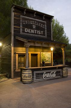 an old fashioned dentist's office with coca - cola barrels on the front and side