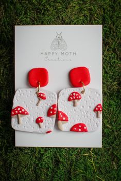 a pair of red and white earrings with mushrooms on them