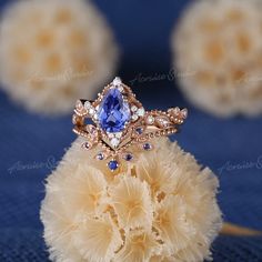 a blue and white diamond ring sitting on top of a piece of yellow fluffy material