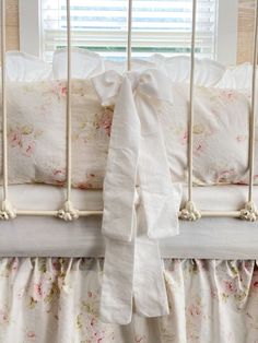 a white crib with pink flowers and ruffled bedspread on the bottom