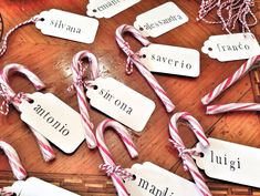 several candy canes with name tags on them sitting on a wooden table next to other items