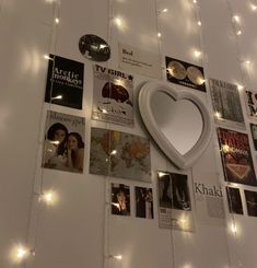 there is a heart shaped mirror on the wall with many pictures and lights around it