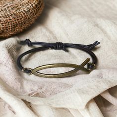 This unique Jesus Fish Bracelet features a minimalist yet striking design, crafted to showcase your faith and style. The bracelet highlights a vintage-inspired brass Ichthys symbol, a timeless emblem of Christianity, securely attached to a dark braided leather band. Ideal for both men and women, this bracelet offers an adjustable fit for any wrist size, making it a versatile piece for daily wear or special occasions. Its combination of genuine leather and brass adds a touch of elegance and durability, ensuring it remains a cherished accessory for years to come. Details: Material: Brass Ichthys Symbol & Genuine Braided Leather Adjustable Knot Design for a Comfortable Fit Bracelet Length: Adjustable to accommodate various wrist sizes Color: Dark Brown Leather & Antique Brass Perfect Gift for Fish Bracelet, Fishing Bracelet, Leather And Brass, Christmas Gift For Him, Adjustable Knot, Knot Design, Fitness Bracelet, Braided Leather Bracelet, Securely Attached