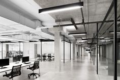 an empty office with glass walls and desks in the foreground, along with two computer monitors on either side of the wall