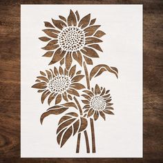 a stencil depicting three sunflowers on a wooden surface