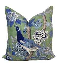 a blue and green pillow with a bird on it's back, surrounded by flowers