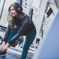 a woman wearing headphones squatting on a bench