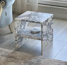 a marbled end table in front of a window