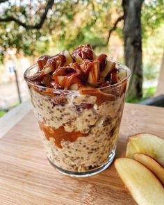 an apple and oatmeal in a glass on top of a wooden table