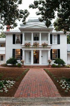 a large white house with black shutters and flowers on the front window sill