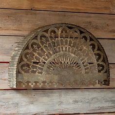 an old metal fan mounted to the side of a wooden wall