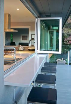 an outdoor kitchen with stainless steel counter tops and stools next to the bar area