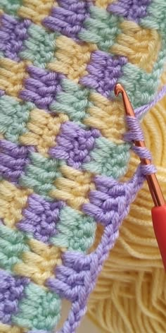 the crochet is being worked on with an orange handled knitting needle next to it