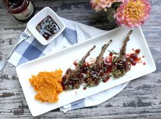 a white plate topped with grilled meat next to sweet potato mashed potatoes and cranberry sauce