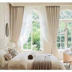 a bedroom with large windows and white curtains