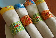 four napkins with colorful designs on them are sitting on a plate next to a bowl