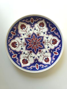 a blue and white plate with red flowers on the bottom is sitting on a table