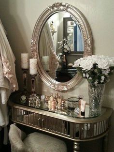 a mirror sitting on top of a table next to a vase filled with white flowers