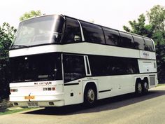 a double decker bus is parked on the side of the road in front of some trees