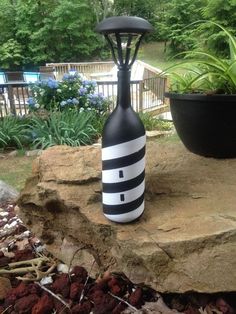 a black and white vase sitting on top of a rock next to a potted plant