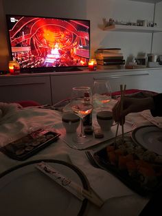 a person sitting at a table with food and drinks in front of a flat screen tv