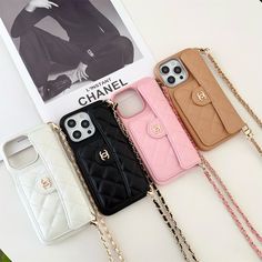 four cell phone cases sitting on top of a white table next to a magazine and chain