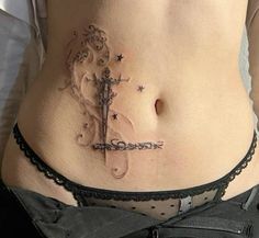 a woman's stomach with a cross tattoo on the side and stars around it