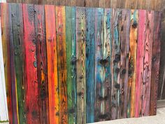 a wooden fence with different colored paint on it