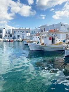 several boats are docked in the water near white buildings and blue sky with fluffy clouds