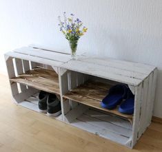 a white shelf with shoes and vase on top