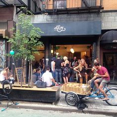 a group of people sitting on the side of a building next to a tree and bike