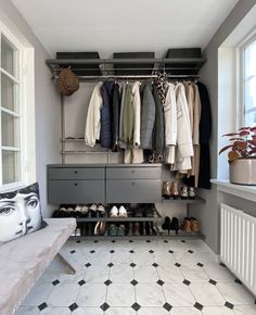 an organized closet with clothes and shoes hanging on the rack, next to a bench