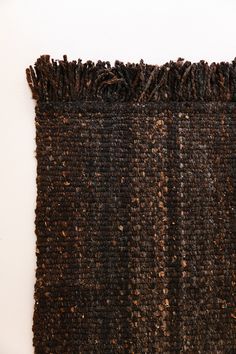 a brown and black rug with fringes on the bottom is shown in front of a white wall