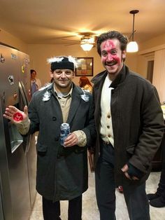 two men dressed up in costumes standing next to each other, one holding a water bottle