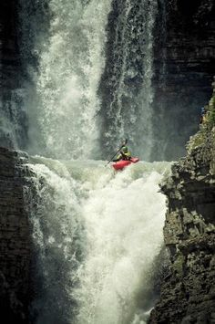 a person in a red kayak on a large waterfall