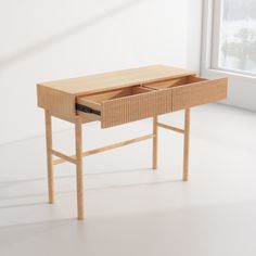 a wooden desk with drawers in front of a white wall next to an open window