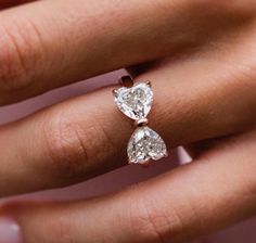 a woman's hand with two pear shaped diamond engagement rings on it, both in gold and white