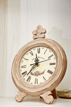 an old fashioned clock sitting on top of a table