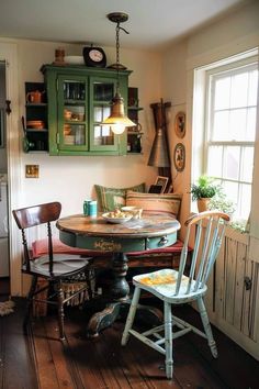 an old fashioned kitchen table and chairs in a room with wood floors, green cabinetry, and white walls