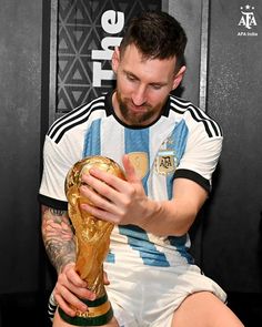 a man sitting down with a soccer ball in his hand and wearing a shirt that says argentina