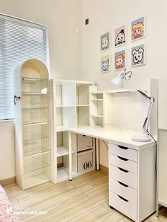 a white desk with drawers and a lamp on top of it in front of a window