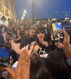 a group of people taking pictures with their cell phones in the middle of a crowd