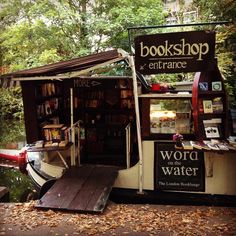 a book shop on the side of a river with bookshelves and water in it