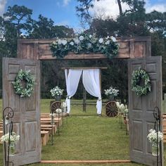 an outdoor ceremony set up with white flowers and greenery on the door, surrounded by wooden chairs